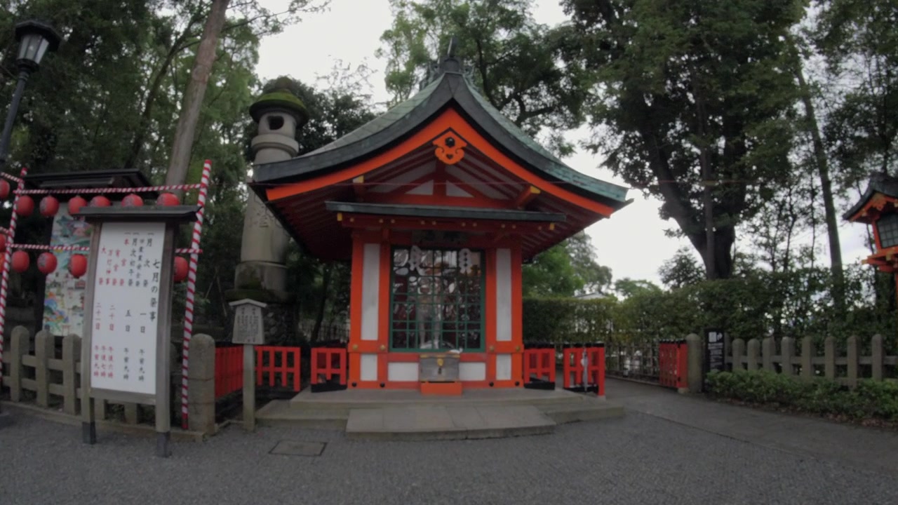 Kameraet nærmer sig langsomt en lille shintohelligdom omgivet af træer i Kyoto, Japan