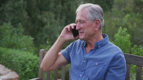 Senior-Caucasian-man-smiling-and-talking-on-the-phone-in-the-garden