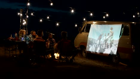 friends watching movie in campsite