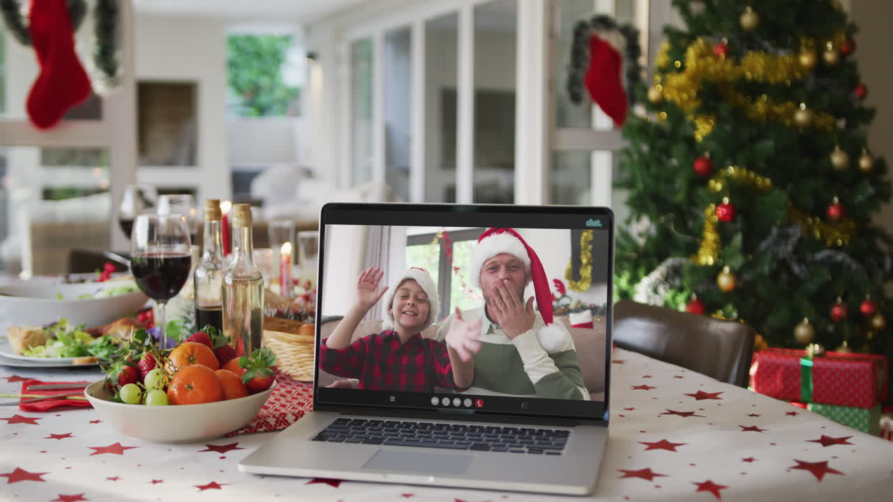 padre y hijo caucásicos felices en la computadora portátil acostados en la mesa de navidad