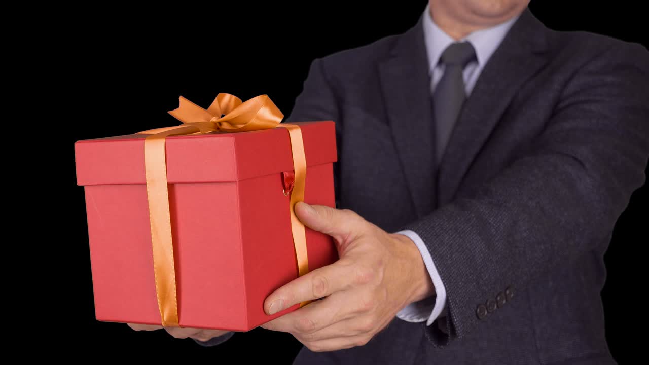 카우카스 사업가 들고 은 선물 상자를 주세요. 초점을 맞추지 않는 것에서 초점을 맞춘 움직임으로. 고전적인 비즈니스 슈트를 입은 성인 남자가 빨간 선물 상자 들고. 알파 채널 크로마 키 투명한 배경. 잠겼습니다.