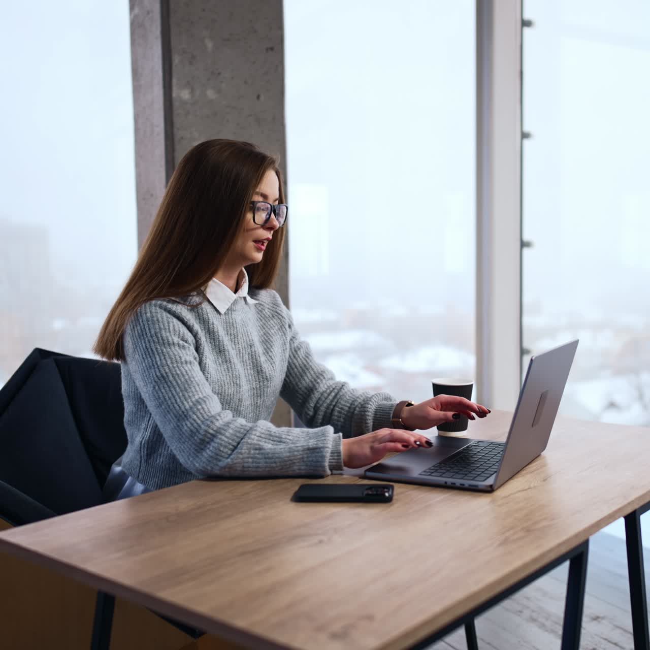 Inizio della giornata lavorativa in ufficio. Impiegata bruna apre il suo portatile e inizia a digitare.