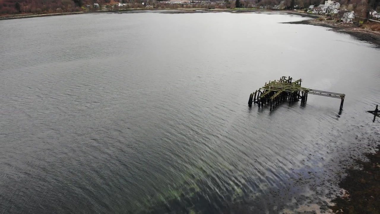 Volo all'indietro del drone che si allontana da una storica struttura di un molo in legno in un lago scozzese