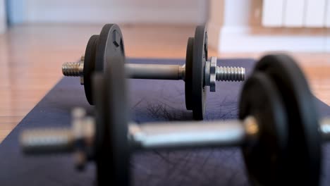 a selective focus close-up on a dumbbell in the background. the fitness equipment lies on an exercise mat, ready for a home workout or strength training session