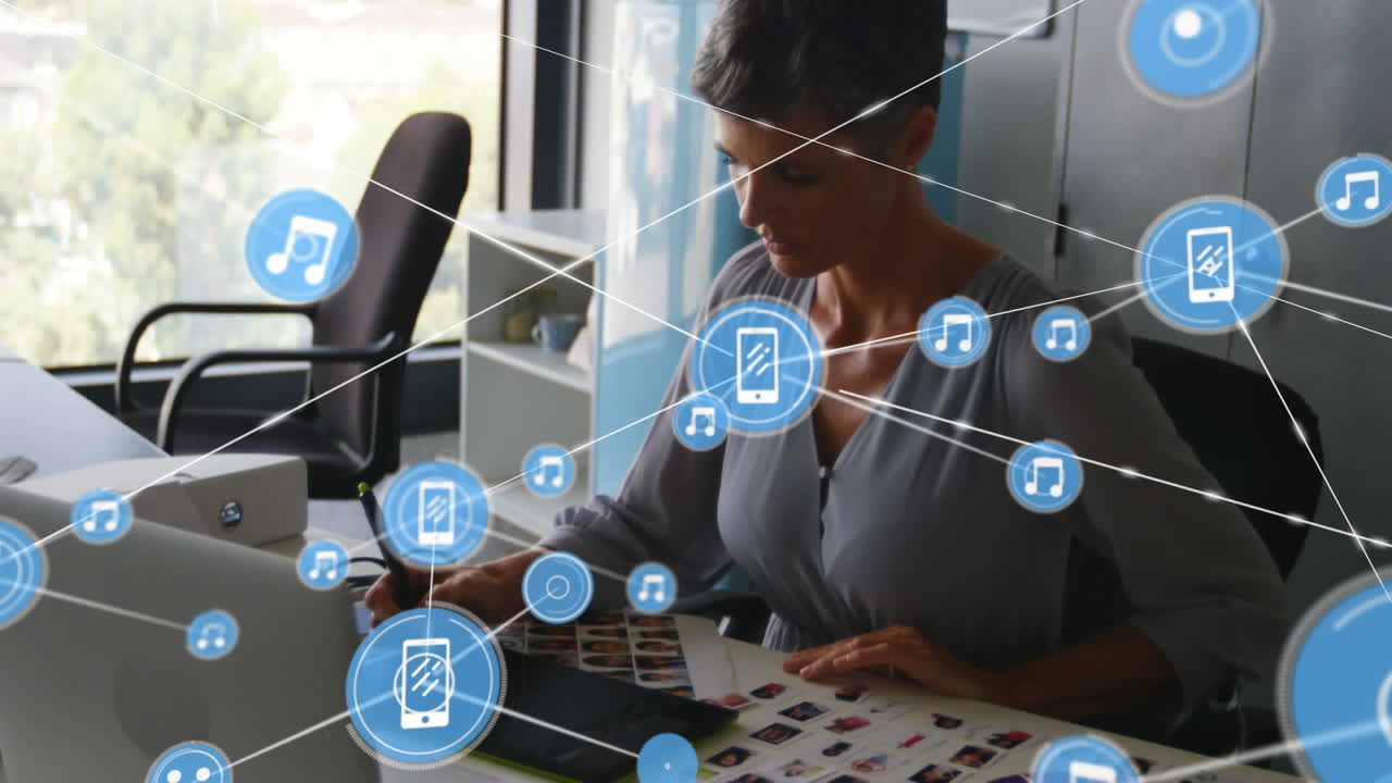 animación de una red de iconos digitales contra una anciana caucásica que usa una tableta gráfica en la oficina