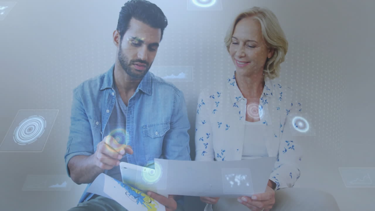 Discussing documents, two people using digital animation interface in office setting