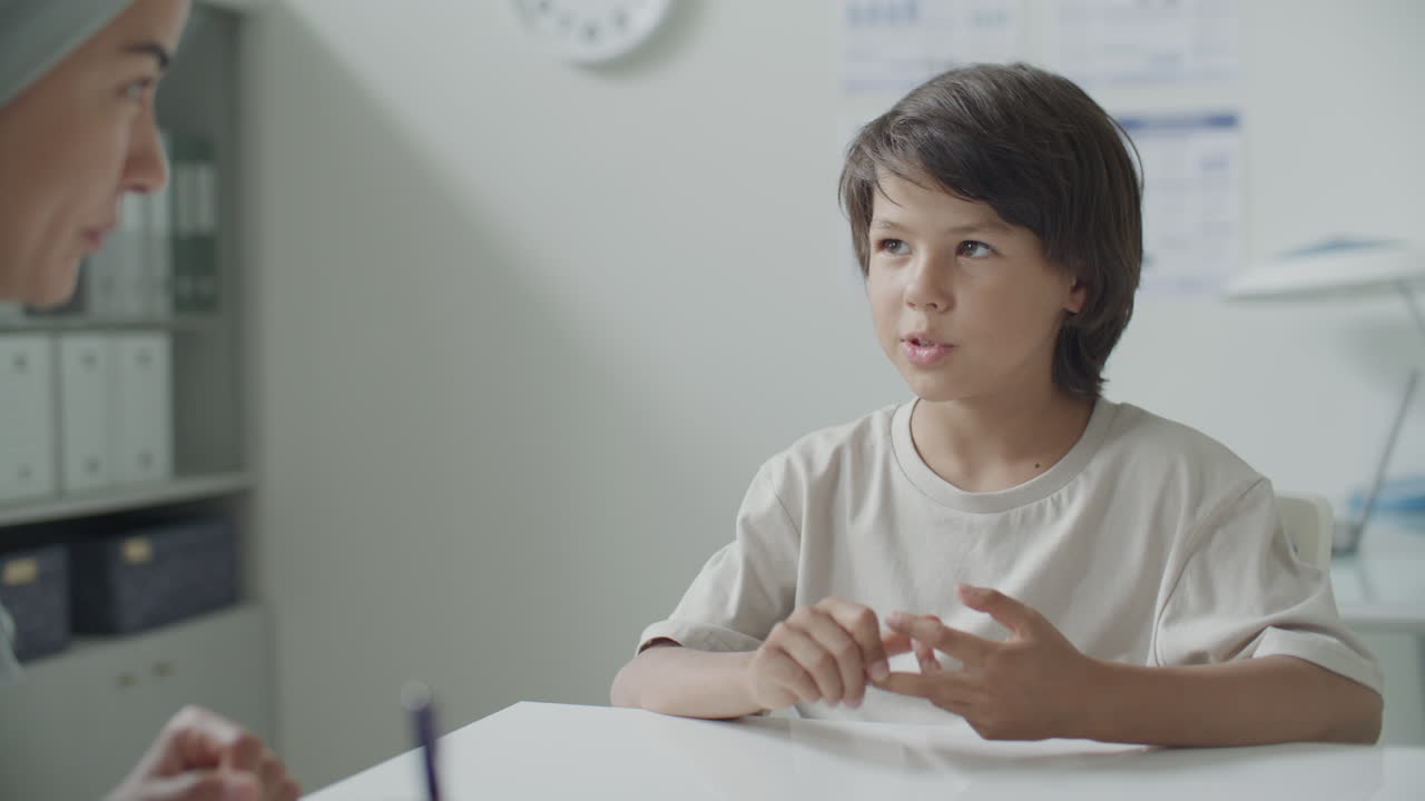 Young Boy Speaking with Female Doctor during Pediatric Checkup in Medical Office