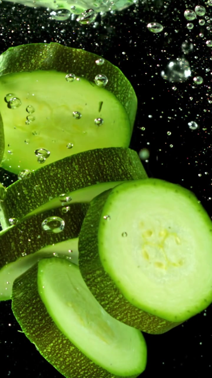 Fette fresche di zucchine immerse nell'acqua con bolle d'aria