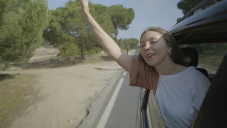 chica sentada en el coche y levantando las manos