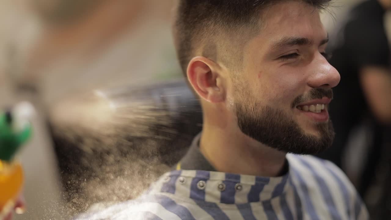 barbero rociando perfume en un cliente en un fondo de barbería