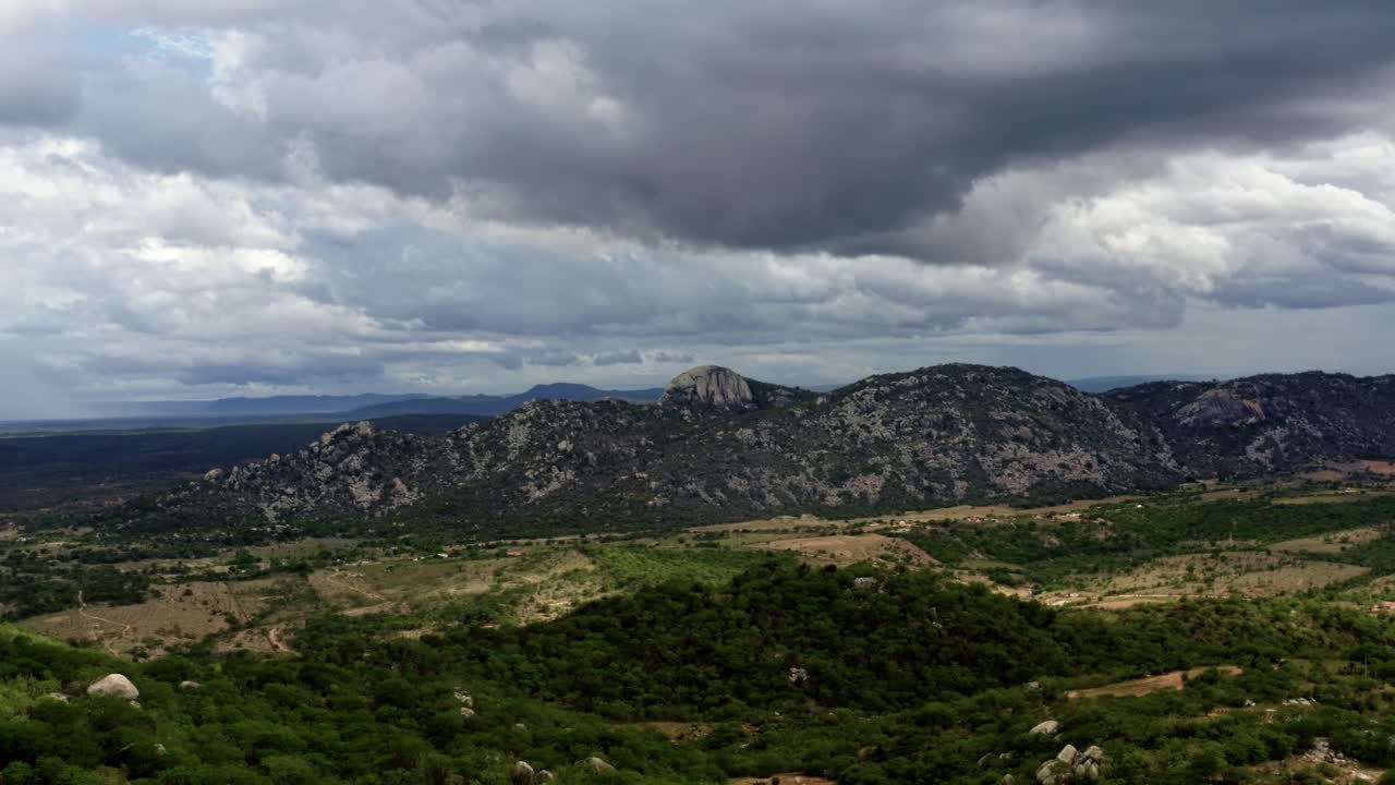 Ripresa aerea con drone in dolly-out, grandangolo estremo della catena montuosa della Pedra de Sao Pedro a Sítio Novo, Brasile, nello stato del Rio Grande do Norte durante una giornata estiva nuvolosa e tempestosa