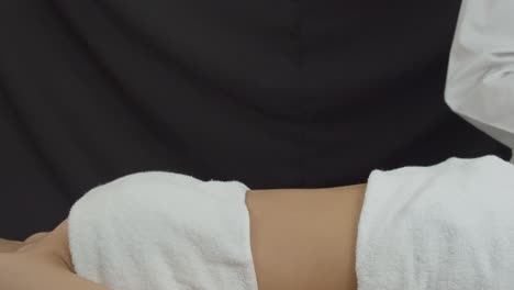미용 클리닉에서 젊고 날씬한 여성이 복부에 초음파 스킨 강화 치료를 받고 있습니다.