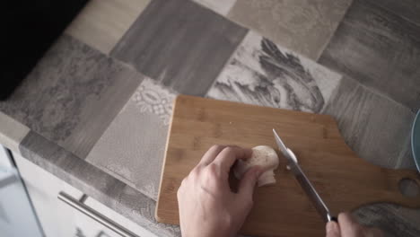 person chopping mushrooms on a cutting board