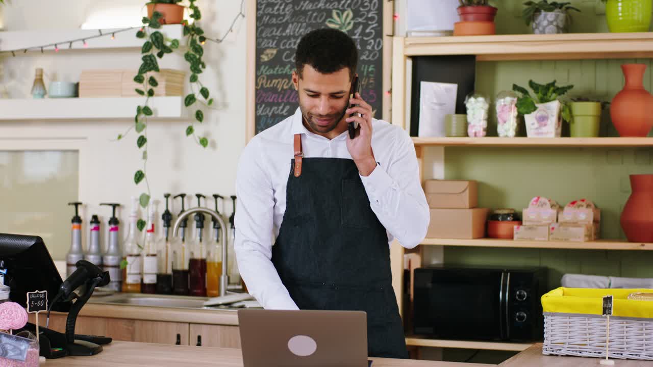 Handsome barista male Afro American using the laptop to type some customer order in the cozy coffee shop concept of small business and entrepreneur