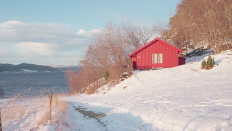 rotes holzhaus am seeufer auf schneebergen in der nähe von vikan in indre fosen, norwegen