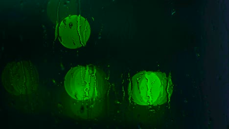 luces verdes de la noche a través de una ventana lluviosa