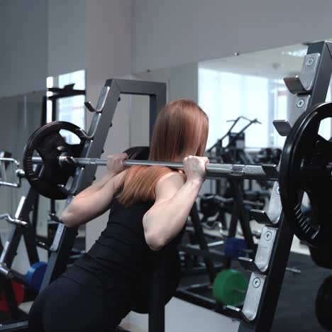 slender woman in sportswear comes to the weight bar and lifts it in the gym near the mirror. healthy lifestyle