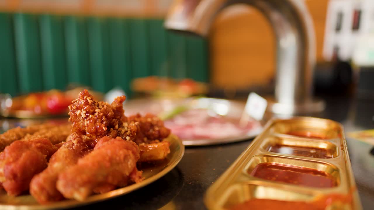 Fried chicken with dipping sauces on grill table, shallow focus, warm indoor lighting, static shot