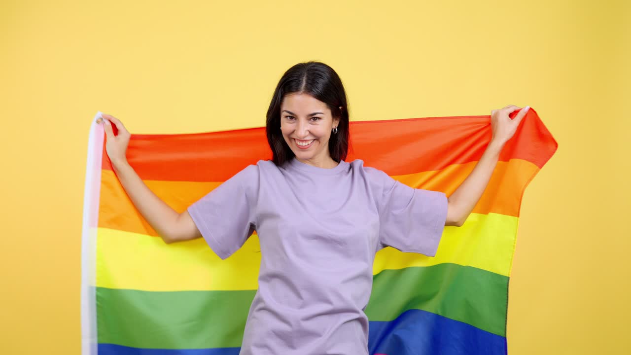 Happy young woman wrapped in a rainbow pride flag