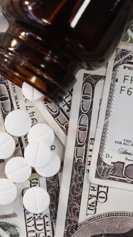 lots of dollar bank notes scattered with pills on table