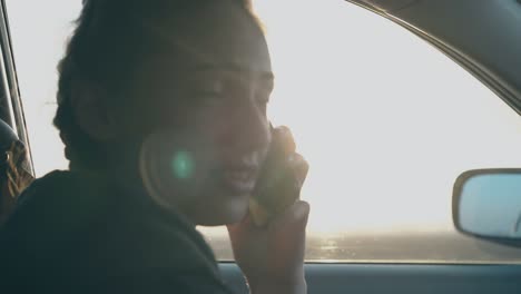 woman-sits-in-car-holds-black-smartphone-and-talks
