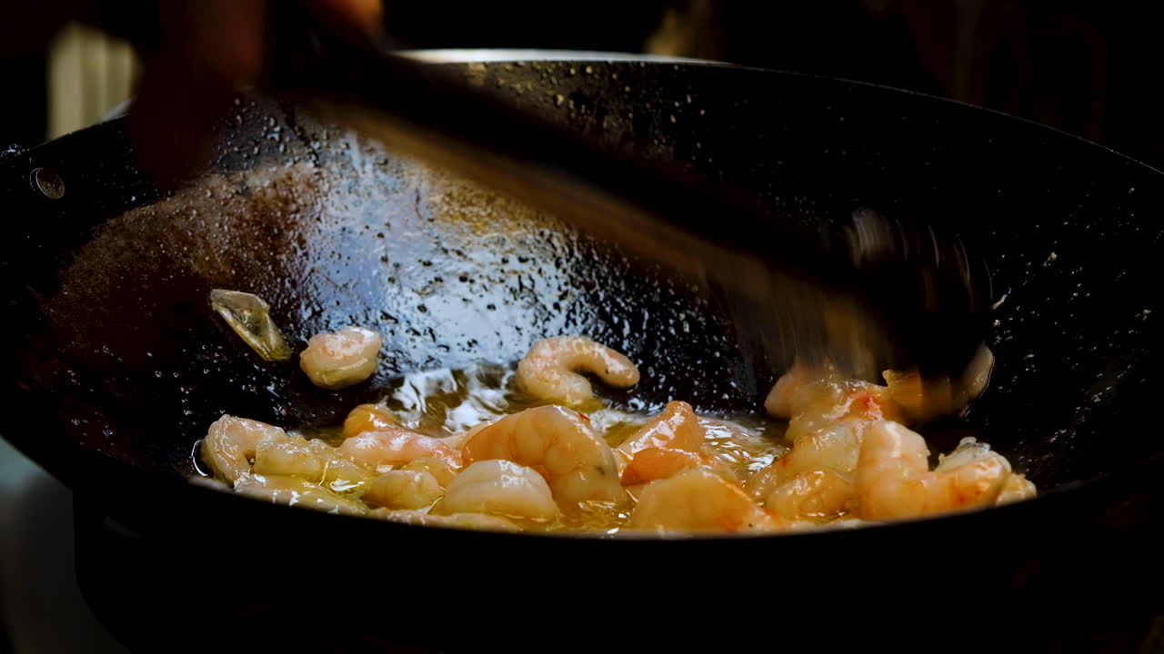 camarones cocidos a fuego lento en el wok que se revuelven con pinzas