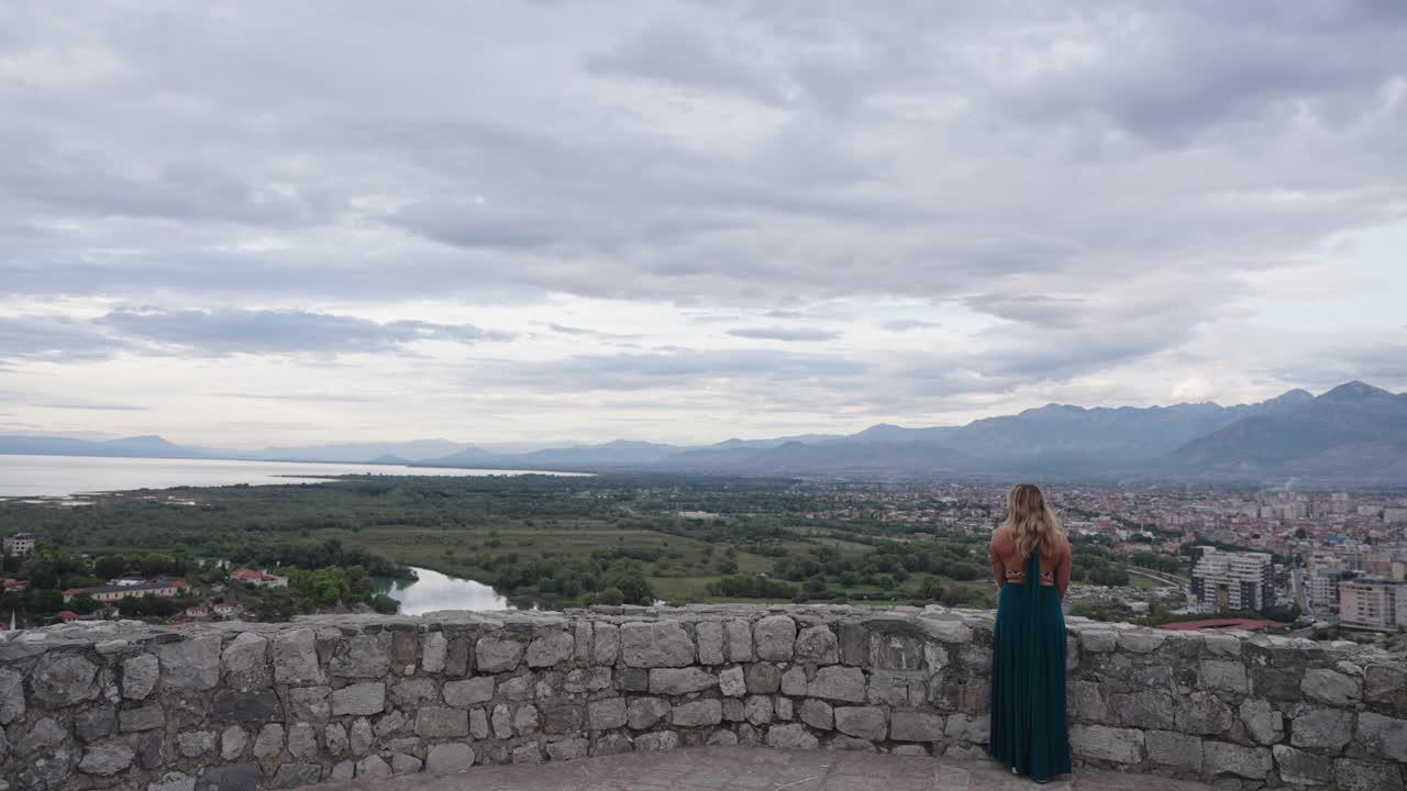 Blonde woman in green dress enjoys stunning view from Rozafa castle in Albania