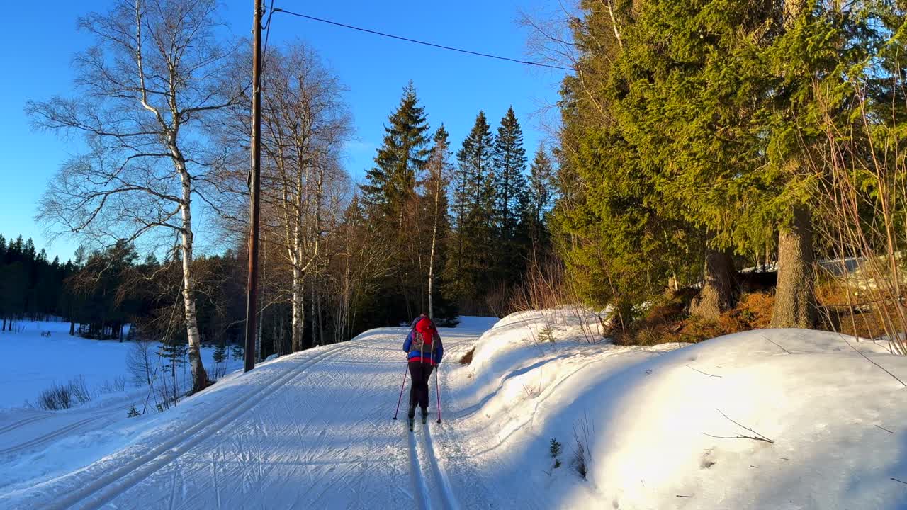 Uphill groomed ski track cross country skiing ski trail path skier Holmenkollen Toppsesteret Skimore Oslo Norway Norge Frognerseteren afternoon arctic golden hour sunny sunset forest follow motion