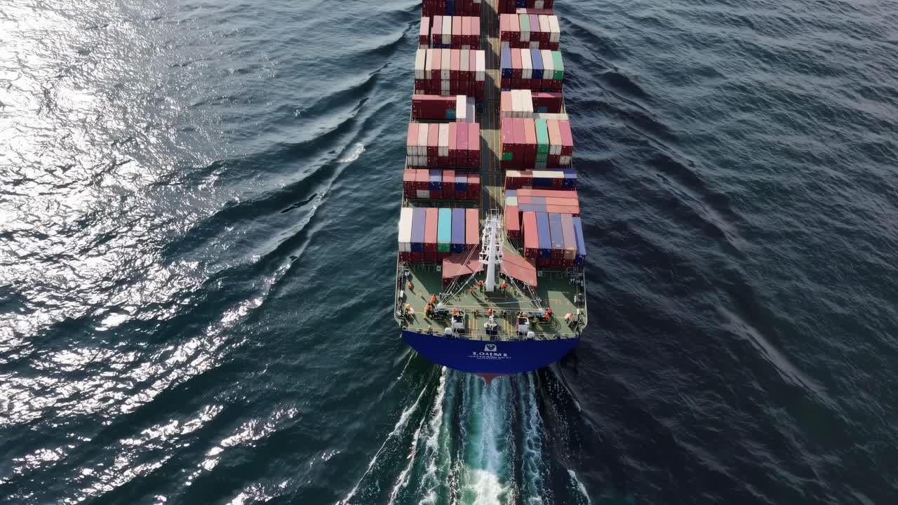 거대한 화물선이 깊은 푸른 바다를 우아하게 건너며 해상 물류와 글로벌 무역 연결을 강조하면서 독특한 색 흔적을 생성합니다.