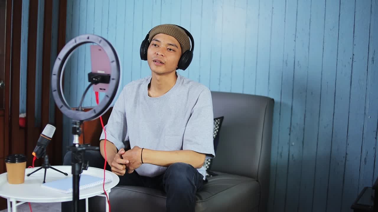 Young content creator with headphones and microphone streams live in home