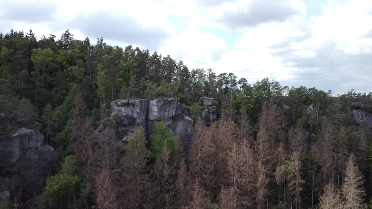 aerial footage of a drone flying close and the above a rockformation in a european nature reserve on a sunny day