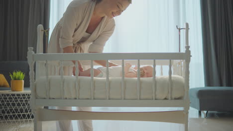 mother caring for newborn baby in crib
