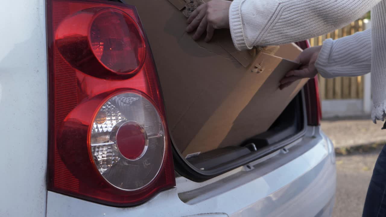 자동차 중간 샷에 골판지 상자를 넣는 여자