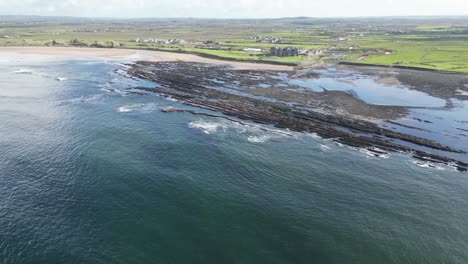 Dughmore-Bay-with-layered-rock-formations-and-waves-crashing,-aerial-view