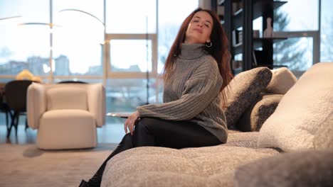 smiling Young Beautiful Woman Holding a Positive Pregnancy Test in her Hands while Sitting on Sofa Smiling Young Beautiful Woman Holding a Positive Pregnancy Test in her Hands while Sitting on Sofa in Living Room at Home Joyful Surprised Pregnant Female Brunette is Happy with Result Rejoices