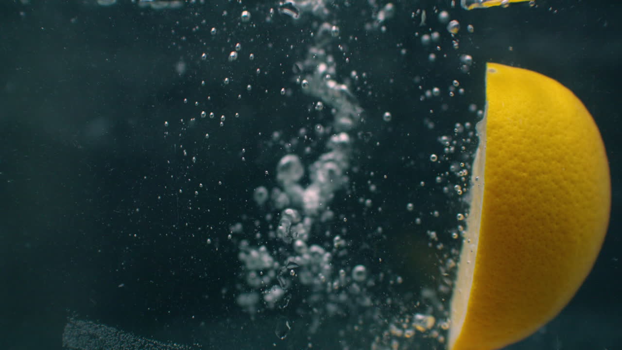 몇 개의 레몬 과일이 물 크 안에 떨어지고 물을 방해합니다. 세 개의 밝은 노란색 레몬 과일을 물 크로 넣고 표면으로 돌아갑니다.