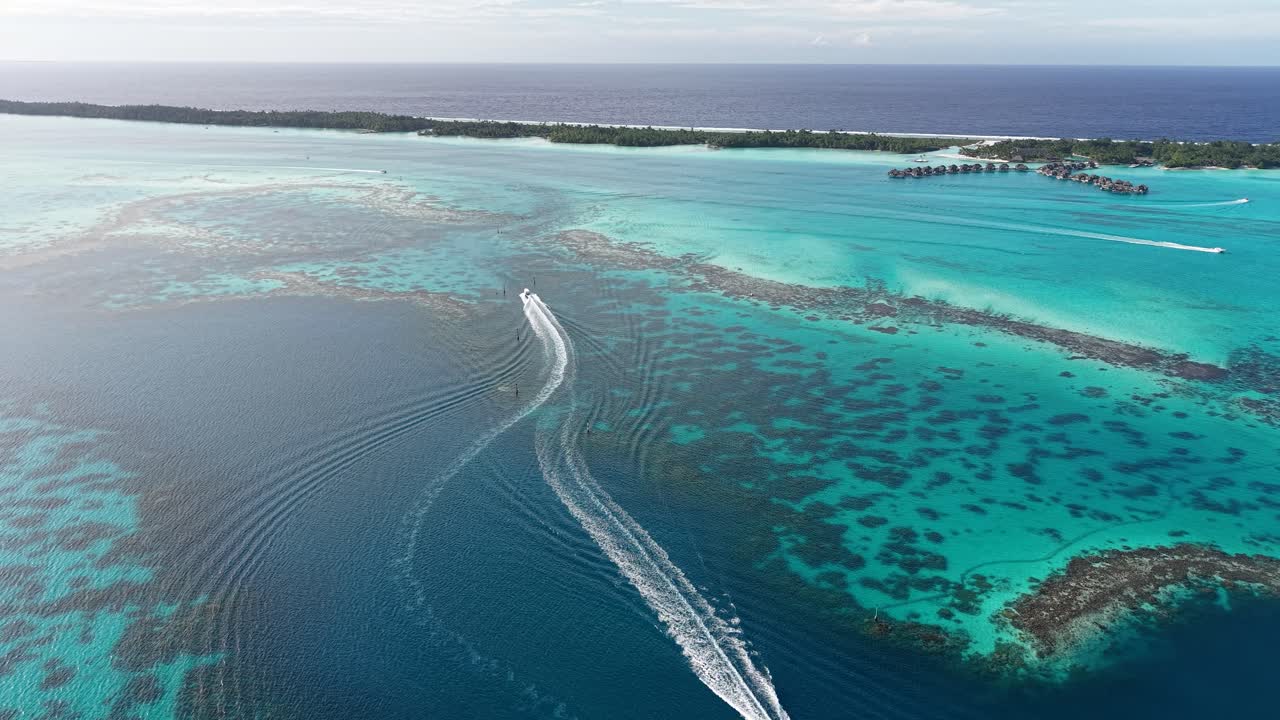 Bora Bora, French Polynesia. Aerial View of Speedboat in ;Lagoon, Coral Reef and Luxury Resort on Motu, Revealing Drone Shot