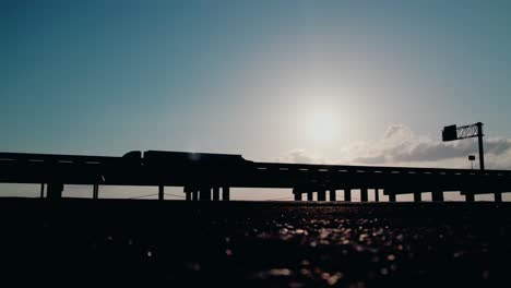 silhouetted semi trailer crossing lake pontchartrain causeway at sunrise