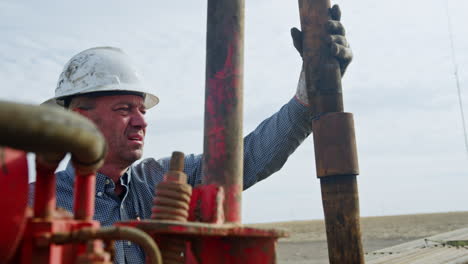 mature caucasian man connecting metal pipes. setting the equipment for the drilling oil or gas.