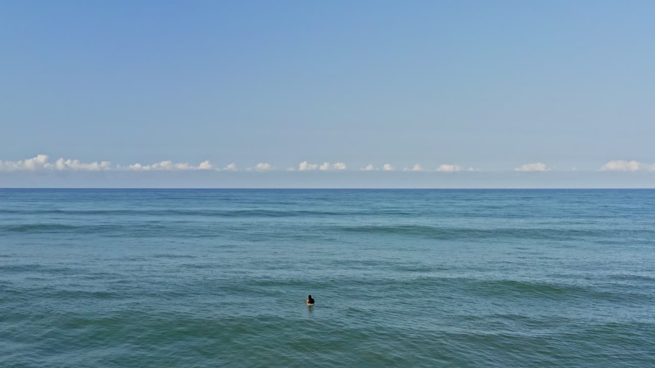 공중:열대 푸른 바다 물과 하늘에서 서핑보드에서 파도를 기다리는 서퍼