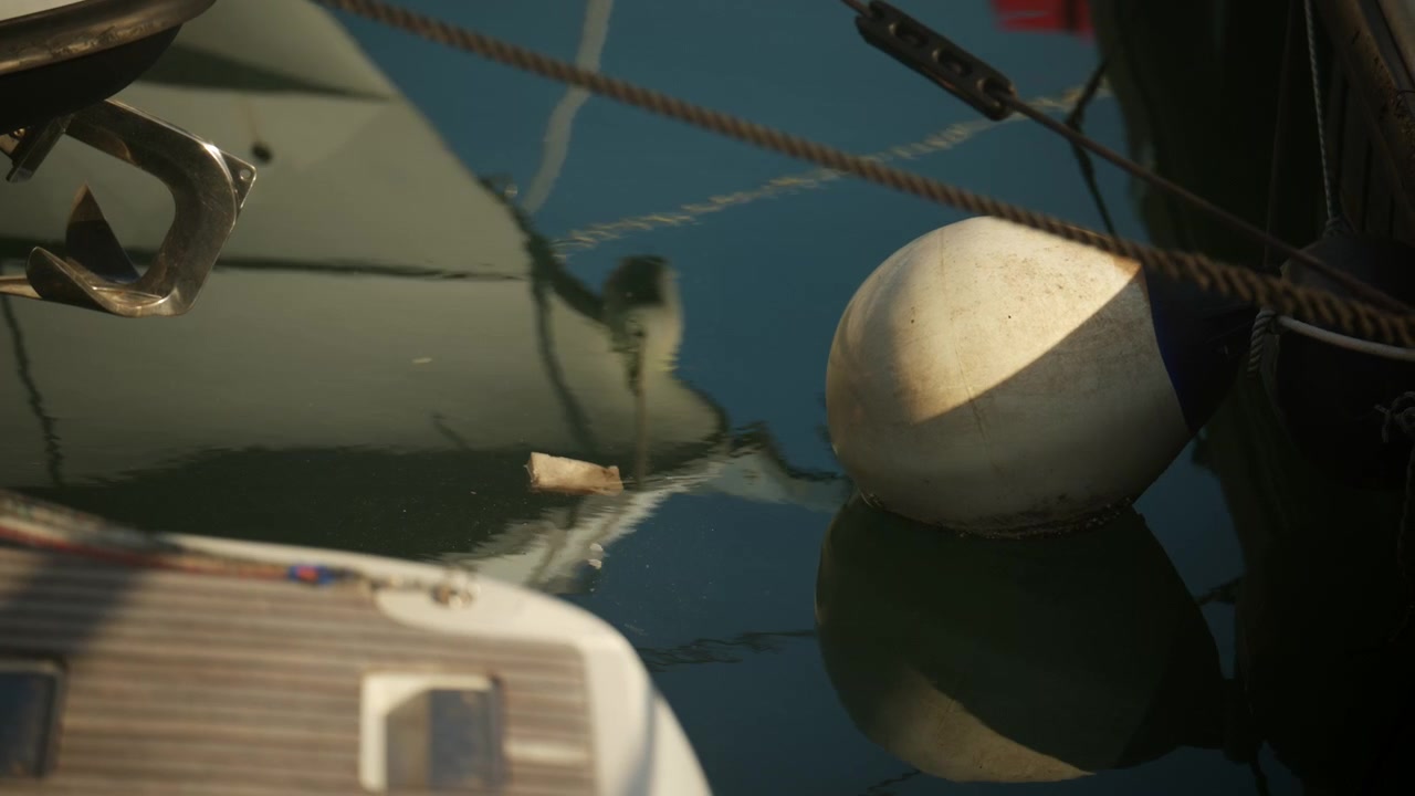 Luxury yacht reflection on calm harbor water with floating debris