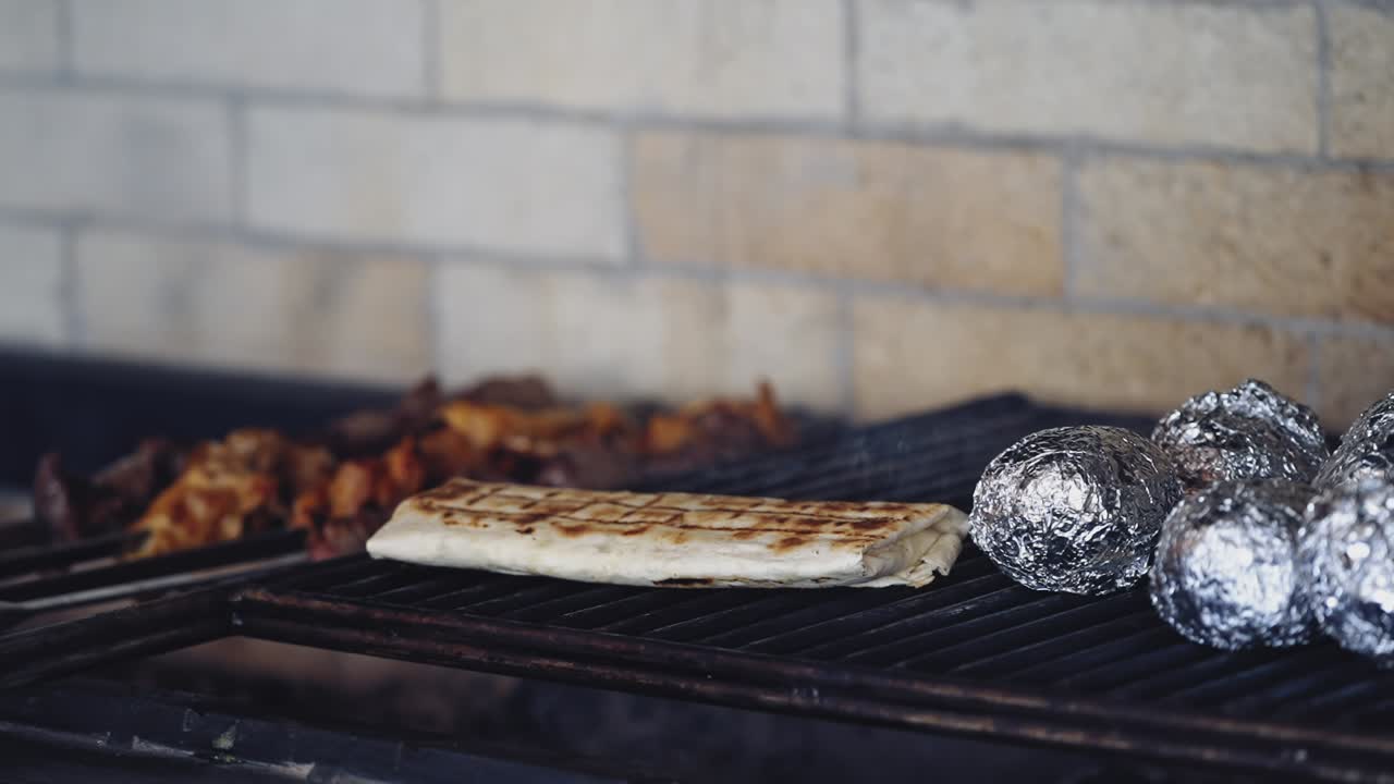Tasty food cooking on a hot grill. Professional chef preparing pita and turns it over on smoke on the stove.