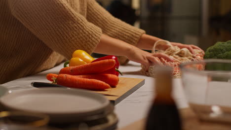 close up of woman getting home from food shopping unpacking and preparing bag of fresh vegetables onto counter in kitchen 1