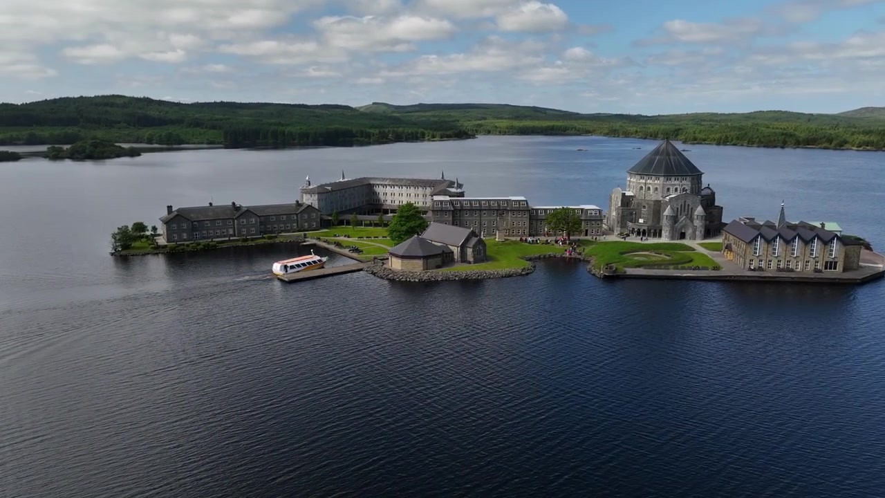 Lough Derg, Donegalin kreivikunta, Irlanti, kesäkuu 2023. Drone kiertää vastapäivään, kun Pyhän Columban pyhiinvaellusristeilyalus lähestyy Pyhän Patrickin kiirastulen laituria Station Islandilla.