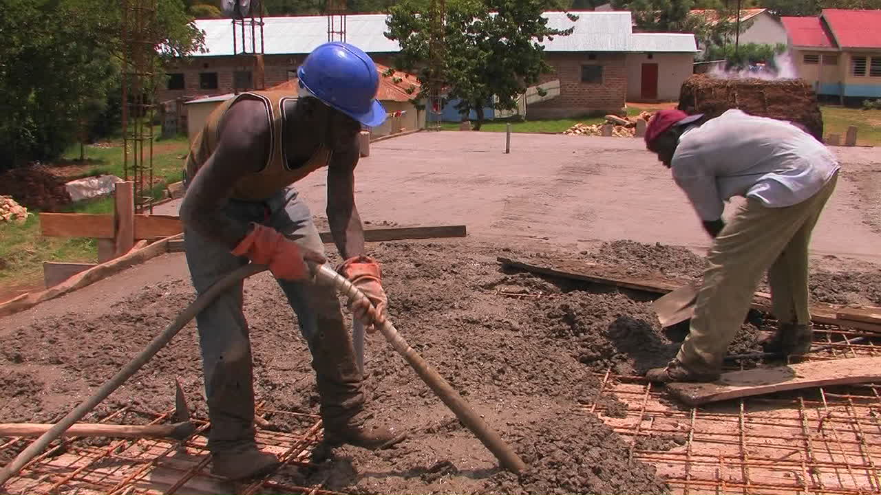 Men dump and spread concrete for the floor of a building