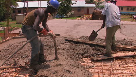 men dump and spread concrete for the floor of a building