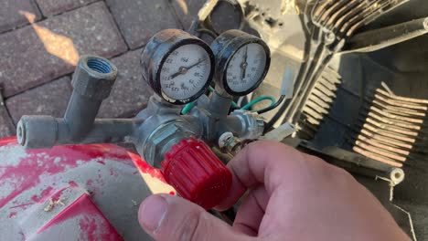 close up of a hand screwing a pressure regulator