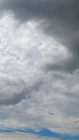 cloudscape covering the skies and summer sun. spindrift clouds spreading along the horizon. low angle view timelapse. vertical video