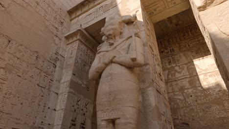 colossal statue guarding medinet habu, luxor, egypt