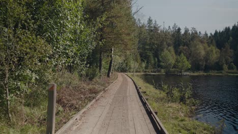 Camino-De-Madera-Junto-Al-Lago-Kypesjön-En-Borås-Suecia-A-Finales-De-La-Tarde-De-Verano---Amplio-Seguimiento-De-Tiro-Hacia-Adelante